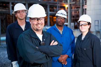 Multi-ethnic Group Of Engineers Working At A Chemical Plant.  Focus On Man (30s) In Foreground.